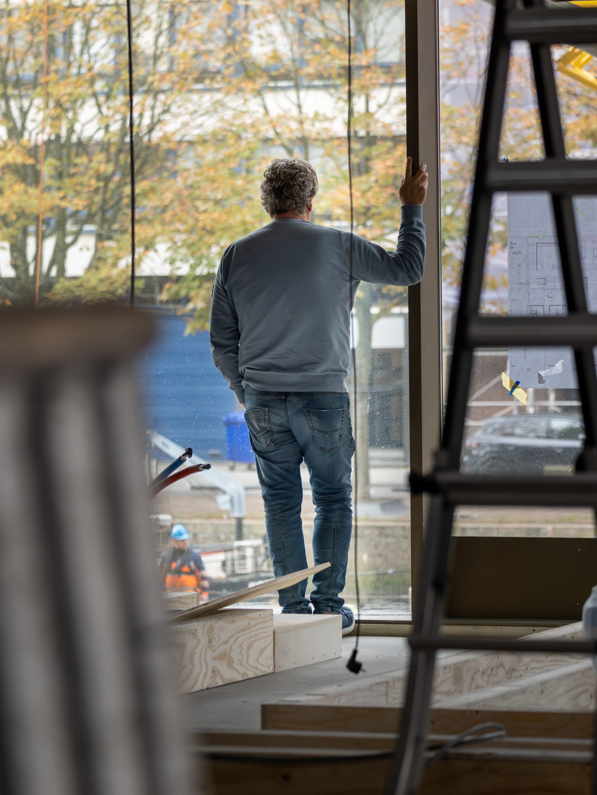 Man bekijkt de voortgang van de verbouwing bij de glazen gevel van Restaurant Fred.